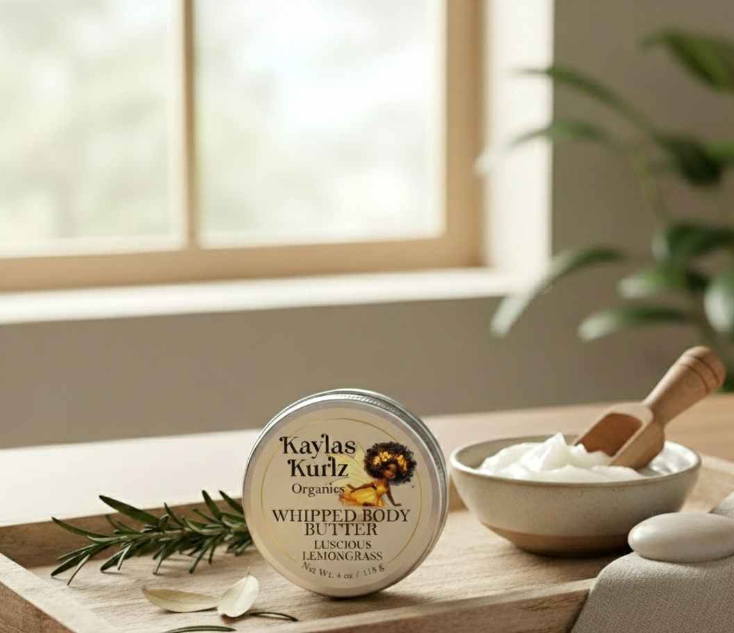 Kaylas Kurlz Organics Lovely Lavenedar Whipped 
Body Butter on a wooden surface with a bowl of product and a plant in the background.