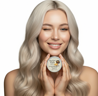 A beautiful woman with loose long curly hair winking her one eye holding a jar of Kayla's Kurlz Organics Radiant Rosemary Whipped Body Butter with a light, creamy texture, gently swirled on top. The packaging features a clean, natural design.
